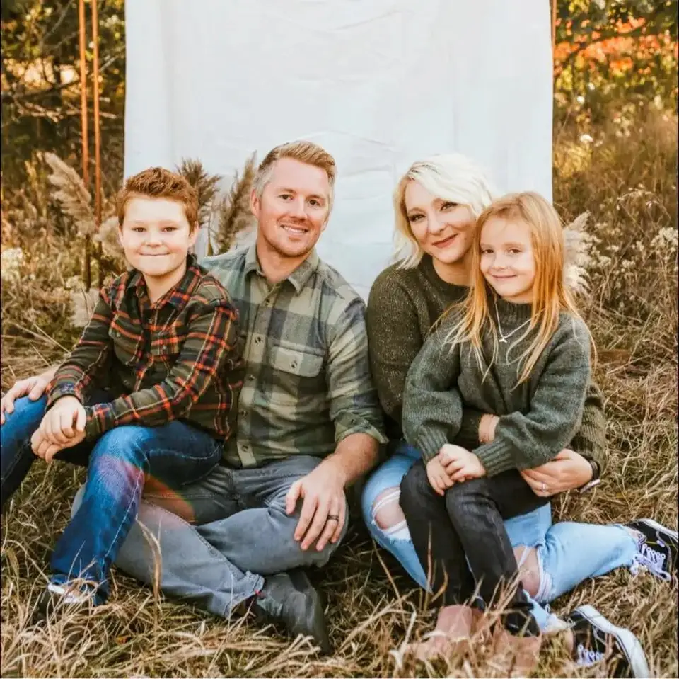 Josh Reeves and his family sitting in tall autumn grass